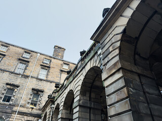 Naklejka premium Historic stone arches and Georgian building facade in Edinburgh, Scotland, UK low angle architectural detail of classic urban courtyard masonry