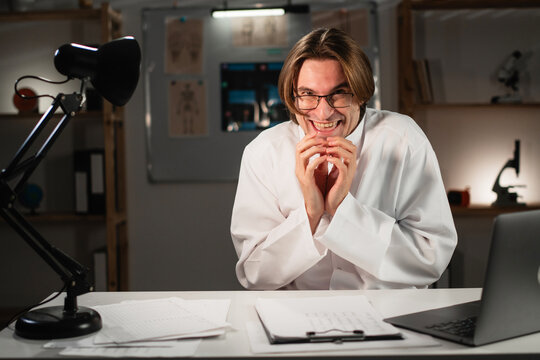 Funny cunning doctor or male nurse having evil plan, scheming something working during night shift at hospital