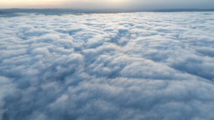 Obraz premium Aerial view sunset sky over clouds drone shot. White cloud layer texture. Scenic natural phenomenon high altitude photography environment scenery background clear horizon