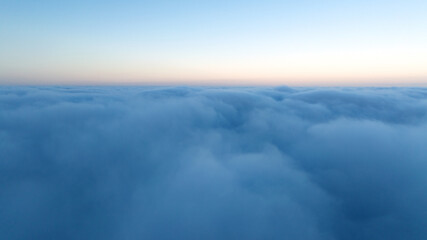 Fototapeta premium Drone shot sunset over clouds high altitude landscape. Sun light shining over white fluffy clouds. Scenic natural phenomenon travel photography atmospheric beauty background.