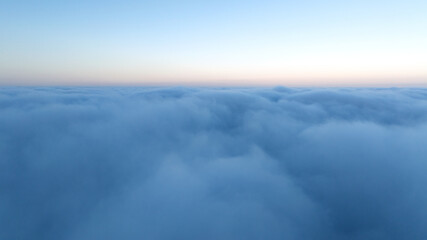 Obraz premium Drone shot sunset over clouds high altitude landscape. Sun light shining over white fluffy clouds. Scenic natural phenomenon travel photography atmospheric beauty background.