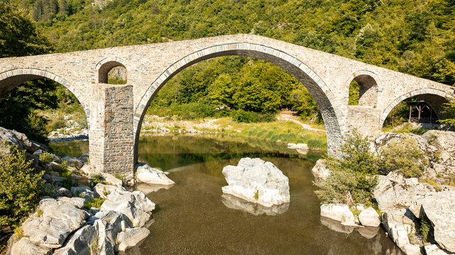 Devils Bridge aerial view Rhodope mountains Bulgaria summer landscape. Ancient stone architecture Arda river water landmark. Drone shot historic bridge Balkan mountains travel photography scenery view