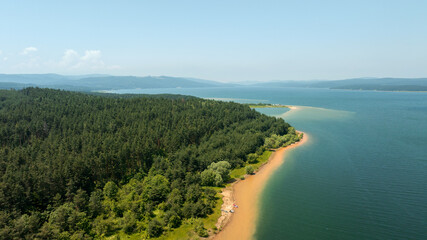 Obraz premium Shiroka Polyana aerial view Rhodope mountains Bulgaria summer. Mountain lake peninsula with camping site and pine forest scenery. Drone shot nature landmark Balkan mountains travel view.