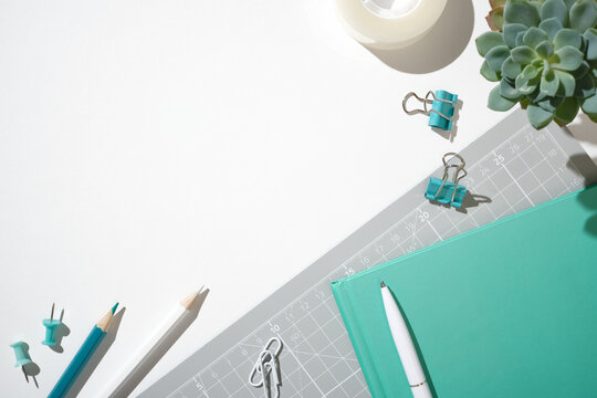 Green and gray workspace flat lay with notebook and clips for creative planning on white background. Copyspace.