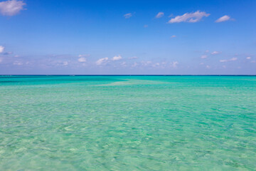 Obraz premium Clear turquoise ocean under blue sky with horizon 青空の下に広がる透明なエメラルドの海