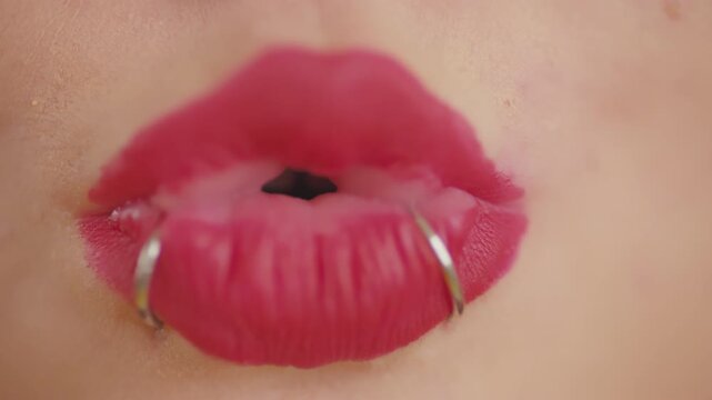 Woman's pierced lips with pink lipstick opening and closing