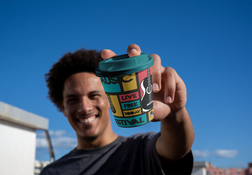 Real photo of Man Holds a take away Cup With Lid in the Sun. PSD mockup.