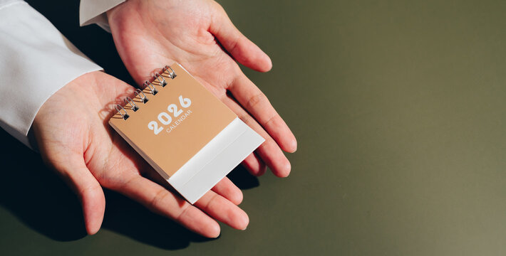 Small calendar hands person planner organization 2026 schedule time management planning date brown white spiral binding office business appointment reminder close up isolated background adult