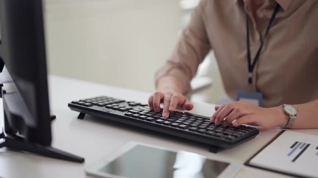 Asian adult professional hands typing on computer keyboard at modern office desk working on business data entry project creating reports for corporate success