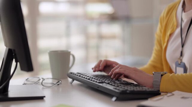Asian professional woman hands typing computer keyboard working diligently office desk with glasses coffee mug productivity online business technology data entry communication project management