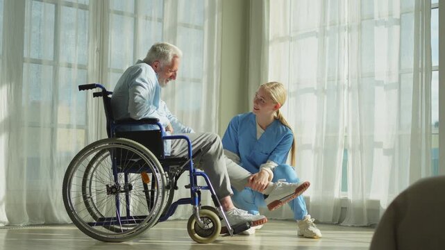 Help support retirement healthcare. Nurse helping old man in wheelchair. Patient and woman in nursing home for medical caregiver. Nurse taking care of paralyzed man in chair for people with disability