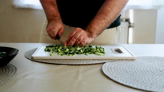 Slicing cucumbers on a cutting board inside a kitchen at midday
