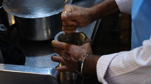 Fresh ginger being mashed for Indian chai preparation at a roadside tea stall