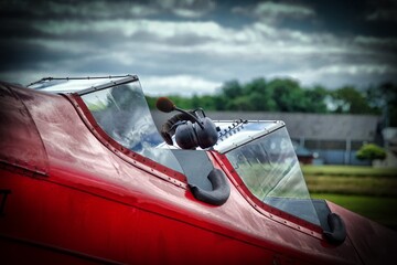 Vintage biplane cockpit with headset seen at airfield during cloudy afternoon in summer months © Malcolm