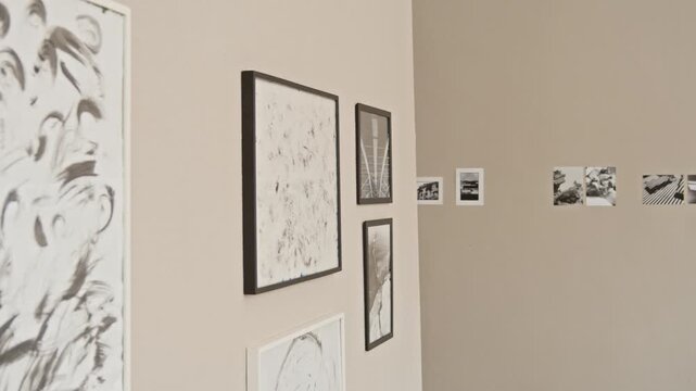 Arc slowmo no people shot of framed abstract black and white paintings and photos hanging on wall in contemporary art gallery with minimalist interior design