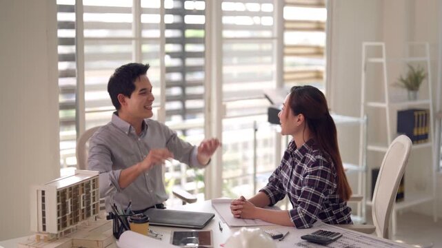 Asian architects celebrate project success giving high five in modern office collaborating on construction models urban design innovation