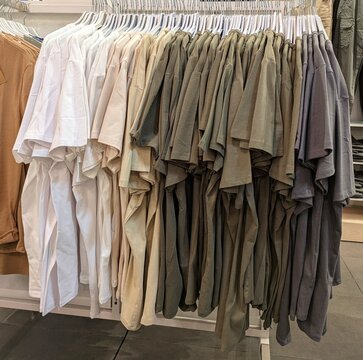 Camisetas de manda corta colgadas en perchas en perchero de tienda de ropa