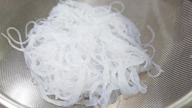 Fresh shirataki noodles or konjac noodles in a metal strainer.