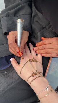 Applying henna mehndi design on female hand close up Middle Eastern tradition. Close up of artist applying henna mehndi design on female hand, traditional Middle Eastern body art and cultural experien