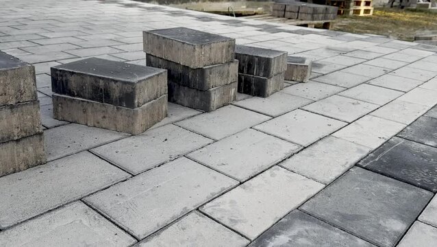 Paved walkway under construction with gray concrete blocks arranged in a pattern