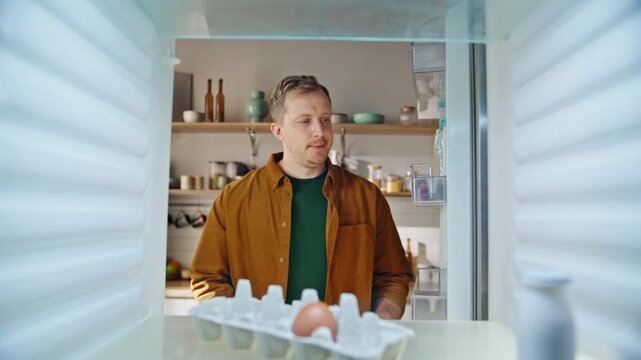 Man open empty refrigerator holding notebook view inside closeup. Serious guy