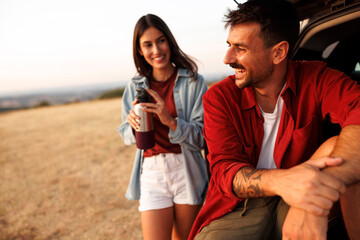 Naklejka premium Couple going for summertime road trip taking a break on a mountain viewpoint