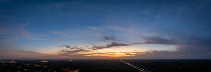 Fototapeta premium Sunset sky over dark land. Bright colorful orange and yellow clouds. Panoramic skyscape
