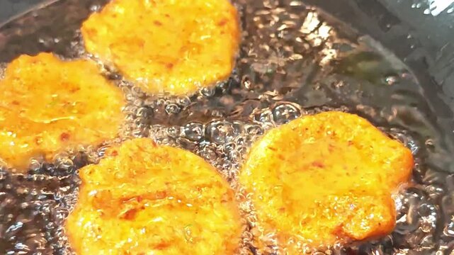 Deep-frying authentic Thai fish cakes (Tod Mun Pla) in a hot wok with bubbling oil.