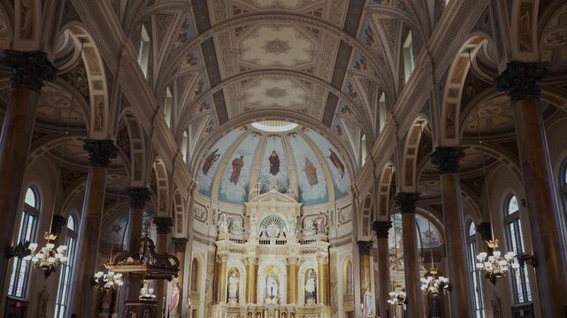 Walking down the middle aisle of a church looking up at lights and Jesus on the cross in an old cathedral church.