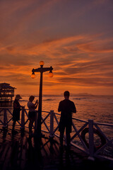 Fototapeta premium a family takes in the breathtaking views from the iconic pier of La Rosa Nautica in Miraflores, Lima. This striking capture highlights why the Costa Verde is a top destination for retired travelers 