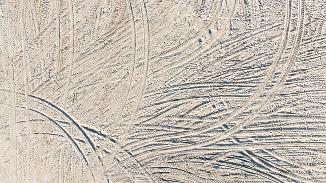 Aerial view tire tracks on sandy beach, Tire tracks on the sand  surface texture background, Tire tracks curve across the soft sand, Wheel tire track on sand texture and background.