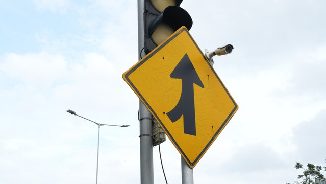 Traffic sign indicating lanes merging left isolated with inactive traffic light. Road safety symbol guiding drivers to merge safely, transportation rules, urban infrastructure, and traffic management.