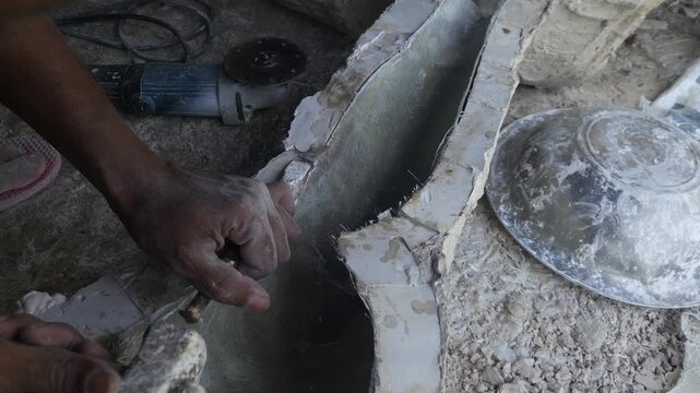 Close-up of a skilled artisan shaping a fibre sculpture using a power tool in a workshop, captured in slow motion. The scene highlights precision craftsmanship, manual labor, India