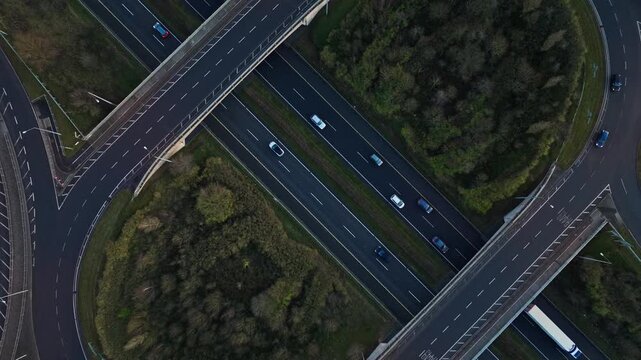 High-quality drone shot capturing an elegant road junction along Ireland&rsquo;s N4 at sunset. Vehicles move steadily across winding lanes surrounded by vibrant green terrain. The warm evening light.