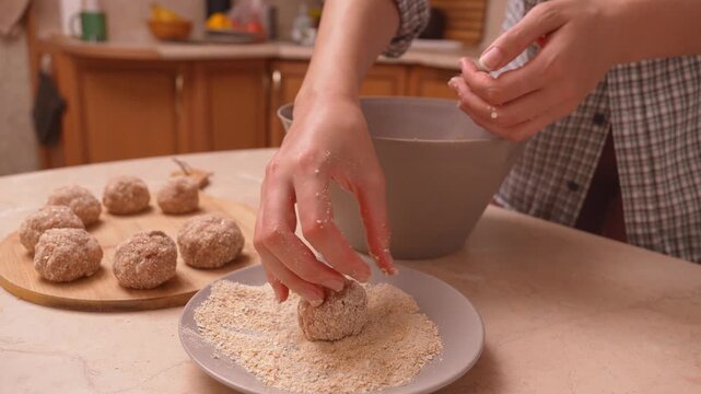 Cooking in breadcrumbs with meatballs. Carefully coat the meatballs with paneer breadcrumbs. The preparation of meatballs and catlets involves rolling breadcrumbs on a wooden surface in a warm kitchen