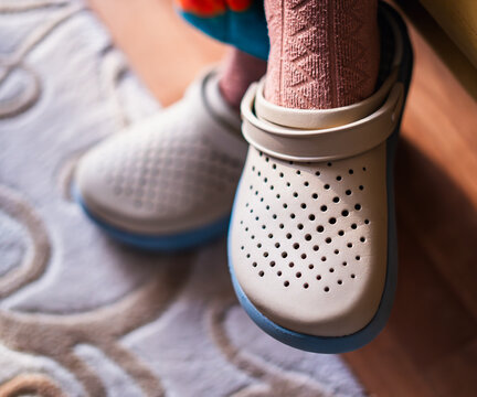 Close-up of adult feet wearing comfortable rubber clog slippers indoors