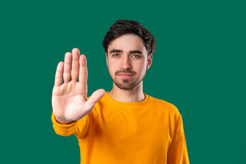 Fototapeta premium Portrait Of Serious Man In yellow Outfit Showing Rejecting Gesture, Stop Palm