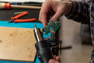 Naklejka premium A professional technician carefully uses a hot air rework station tool to repair components on a green printed circuit board during an intricate electronic maintenance session