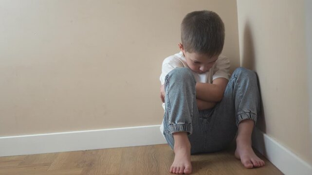 Young girl sitting on the floor. Sad child sits on a corner and is punished. Lifestyle a teenage girl is traumatized by a violent incident. A little girl sitting on the ground.