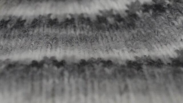 A close-up view of a knitted fabric with intricate black and white patterns, showcasing detailed textures and stitches across eight seconds of slow, steady camera movement.