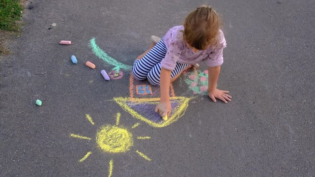 Children drawing with chalk on the asphalt. Selective focus.