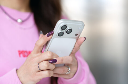 Kyiv, Ukraine. March 20, 2026. Woman using smartphone Apple iPhone 17 in pink sweater, close up of hands with modern device and mobile communication concept