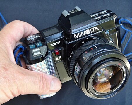 Hand holding Minolta 7000 autofocus film SLR camera