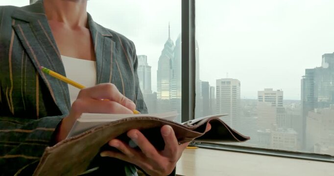 Businesswoman Writing Notes in Office with City View