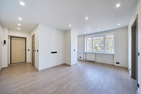 Modern empty apartment interior ready for sale or rent. Bright minimalistic hallway with wooden floor in a new residential building. Real estate investment, property development and housing market.