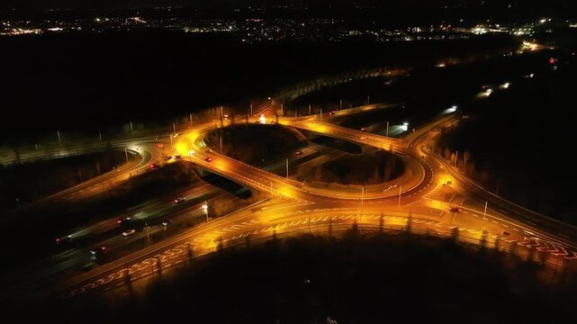 Night drone shot of highway junction on N4 Ireland with glowing traffic lights and moving cars.