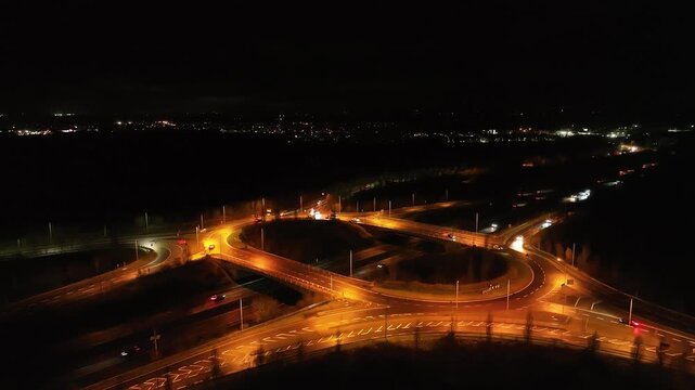 Cinematic drone footage of night highway interchange with bright lights and moving cars on N4 Ireland.