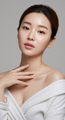 Naklejka premium Korean woman with glowing healthy skin. Female model posing with natural makeup for skincare advertisement. Concept of eco cosmetic, spa treatment and facial radiance in beauty industry.