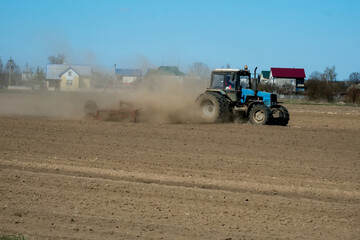 Fototapeta premium Farmer in tractor preparing land with seedbed cultivator as part of pre seeding activities in early spring season of agricultural works at farmlands.