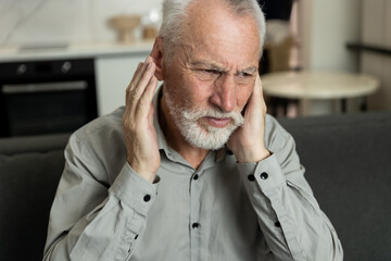 Senior man suffering ear infection and headache at home